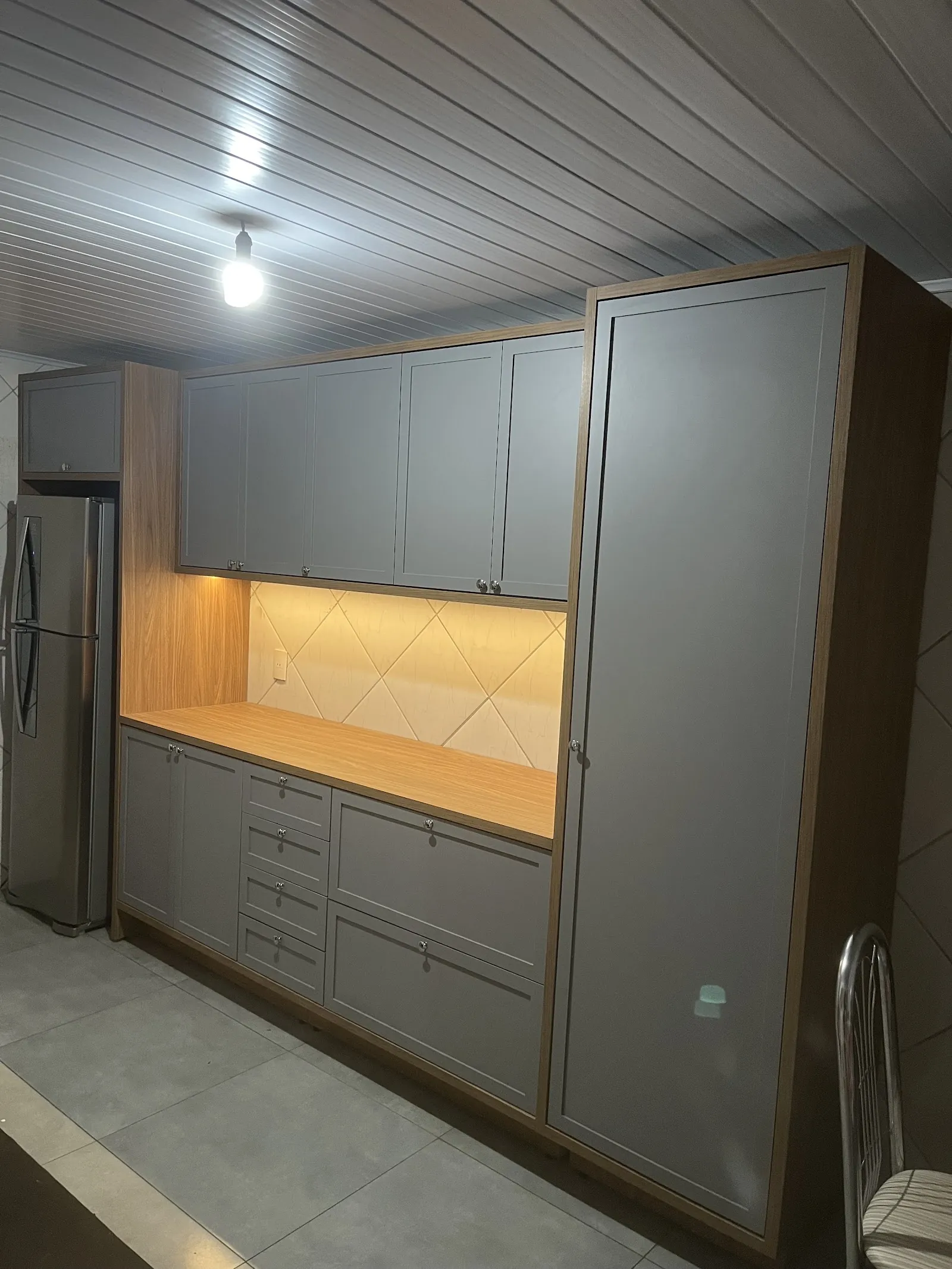 Cozinha planejada cinza com tampo amadeirado e iluminação sob os armários